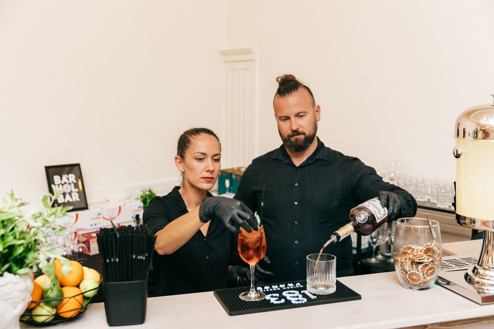 A BÁRHOLBAR két bartendere italt tölt és koktélt készít egy rendezvényen